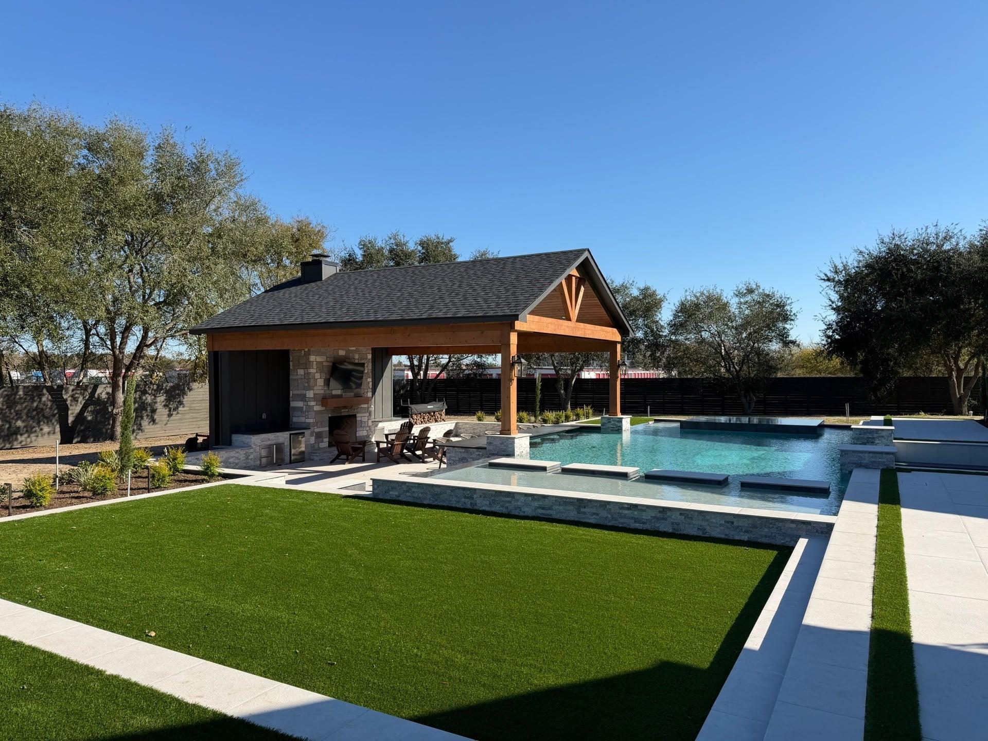 Custom outdoor living space with pool, pavilion, and fireplace built by Ace Outdoors Solutions