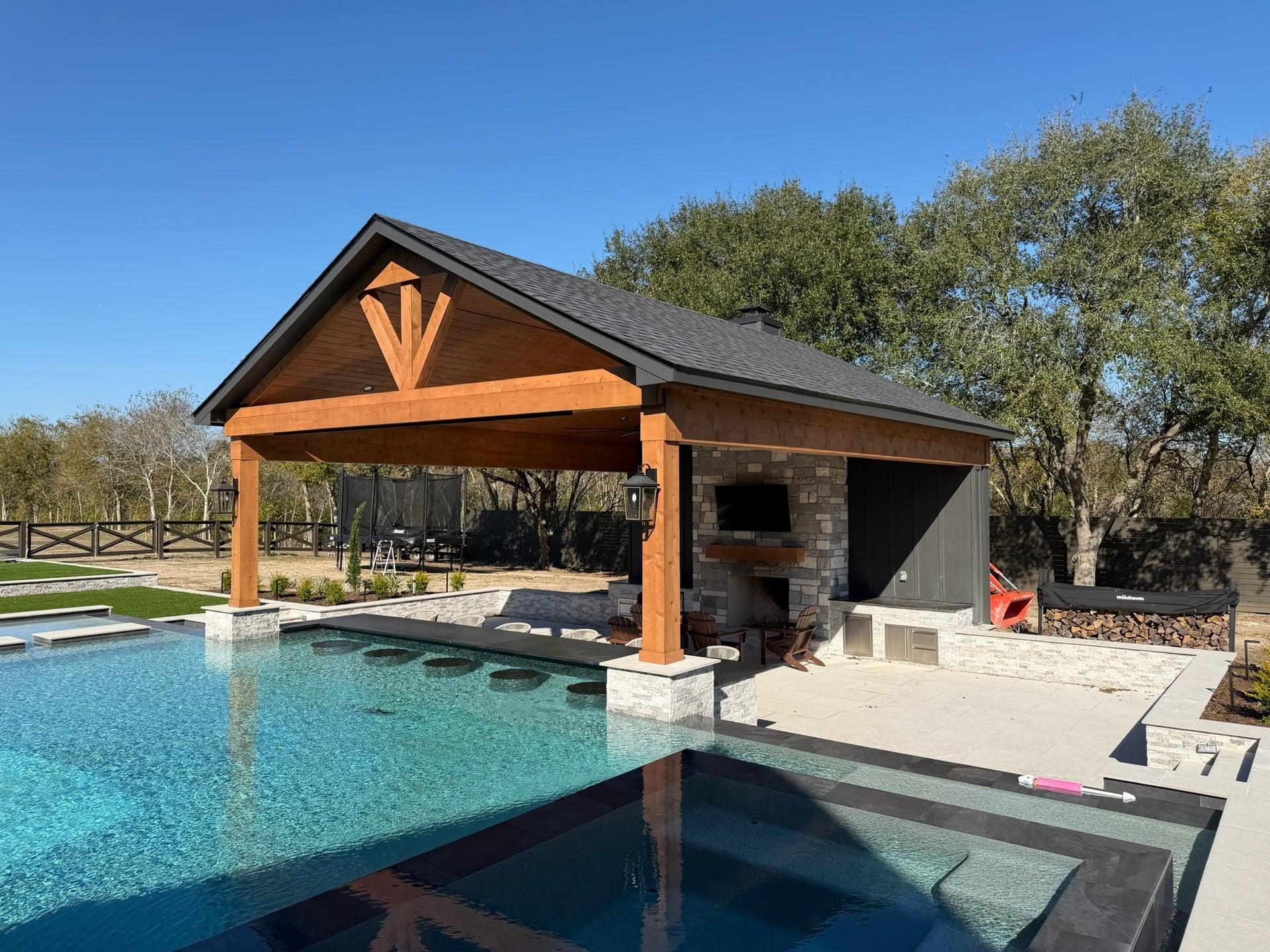 Gable roof pavilion with stone fireplace and pool-side seating