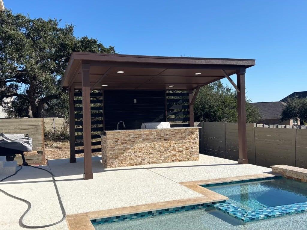 Covered pergola with recessed lighting over outdoor kitchen bar by pool